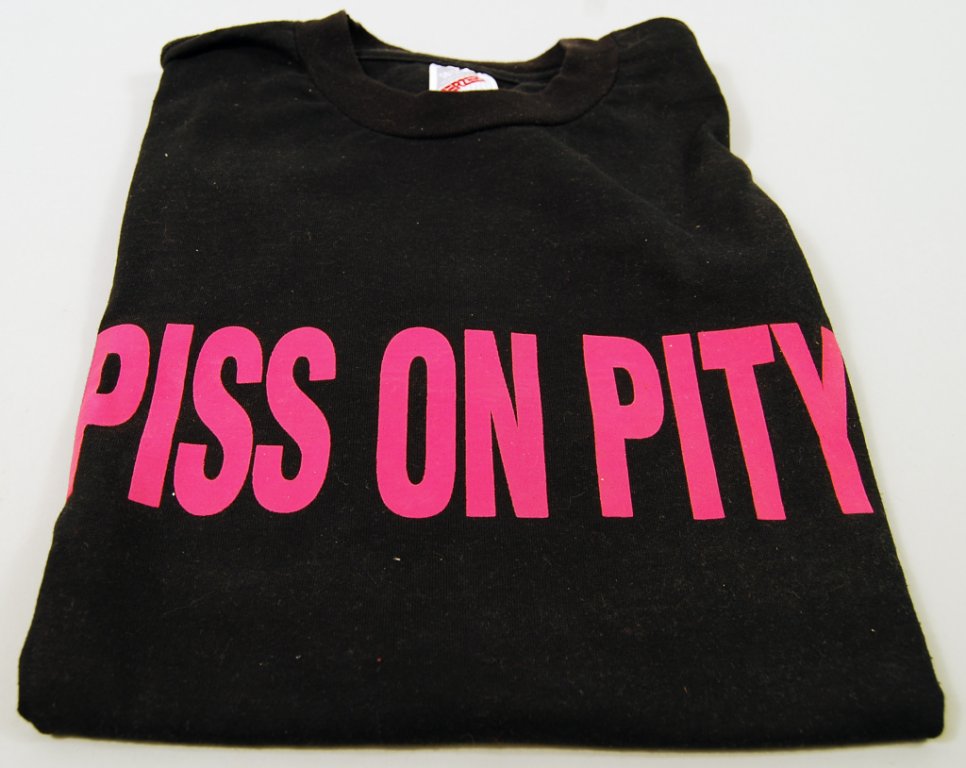 A black T-shirt with the phrase “Piss on Pity” in hot pink letters.