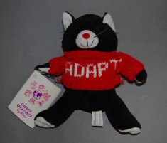 A small black cat stuffed animal wears a red ADAPT T-shirt.